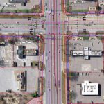 Aerial view of an urban intersection with buildings and traffic markings.
