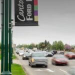 Busy street with moving cars near a car dealership.