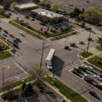 Black road, green grass and trees, and turning white truck