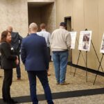 People viewing an indoor photo exhibit with displayed images on easels.
