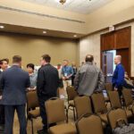 A group of men in suits conversing in a conference room.