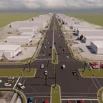 A wide urban road with multiple lanes and cars at an intersection.